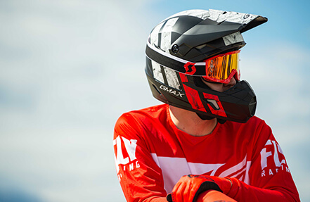 Young man wearing a red shirt and black gmax helmet while looking out into the distance young man wearing a black and red gmax helmet while sitting on his bike