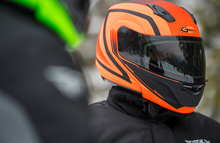 Man wearing a orange and black gmax helmet while riding with a friend Man wearing a Gmax Helmet in the snow